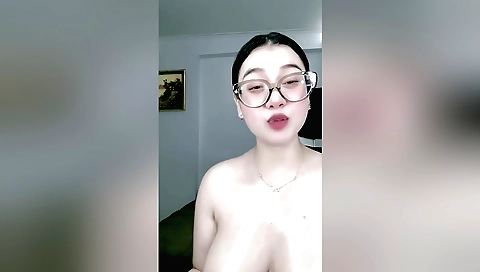 Busty brunette wears glasses on a chair and masturbates